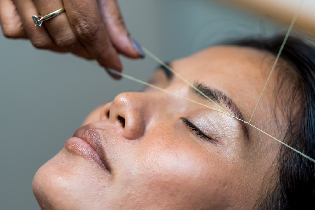 Lash artist applying individual eyelash extensions with tweezers