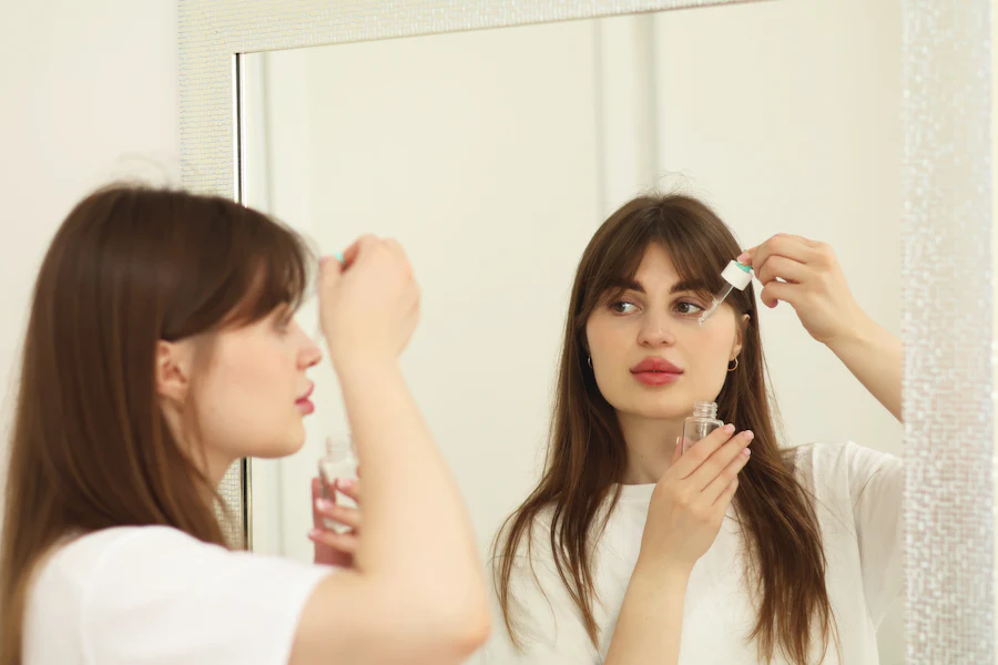 Young woman applying a face serum as part of her skincare routine