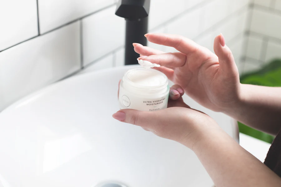Woman applying face cream at the bathroom sink to dry skin